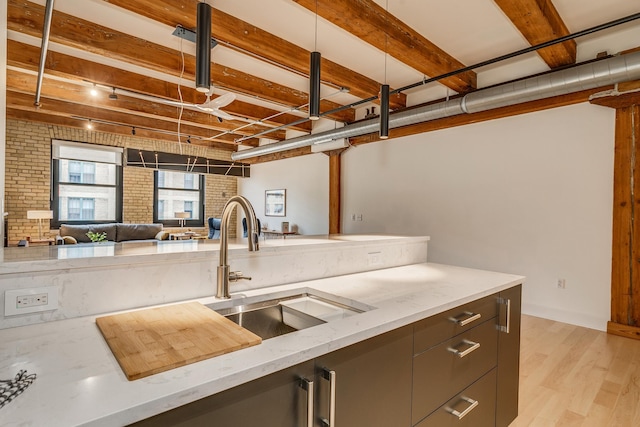 kitchen featuring light hardwood / wood-style flooring, light stone counters, sink, and brick wall