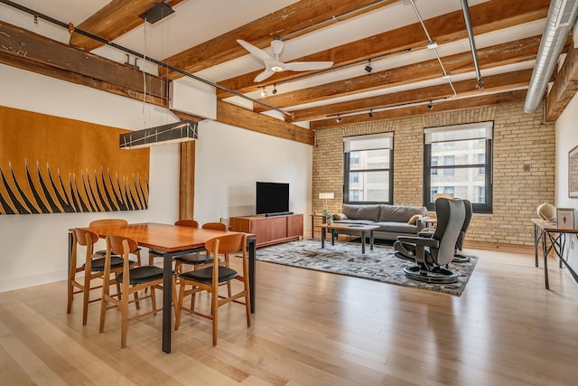 dining area featuring brick wall, ceiling fan, beamed ceiling, and light hardwood / wood-style flooring