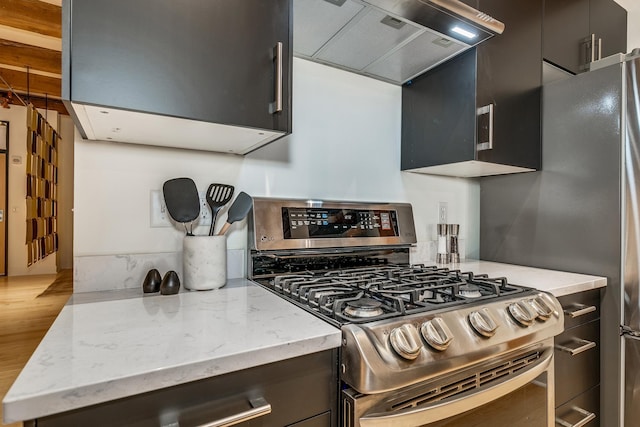 kitchen featuring wood-type flooring, light stone counters, stainless steel range with gas cooktop, and custom range hood