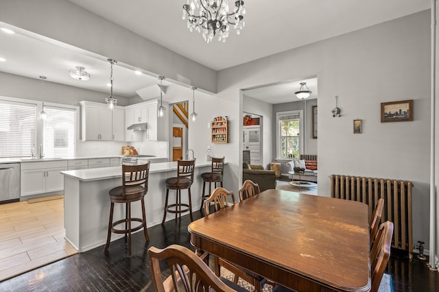 dining space with light hardwood / wood-style flooring, radiator, a notable chandelier, and sink