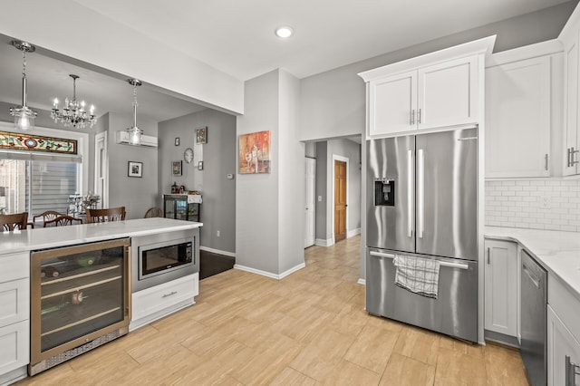 kitchen with white cabinets, beverage cooler, decorative light fixtures, stainless steel appliances, and an inviting chandelier