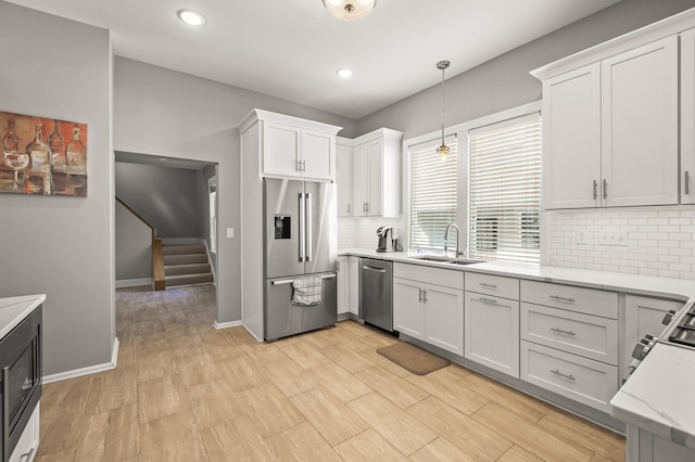 kitchen featuring sink, pendant lighting, stainless steel appliances, and white cabinets