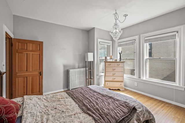 bedroom with radiator heating unit, light hardwood / wood-style floors, and an inviting chandelier