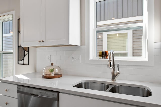 kitchen with sink, stainless steel dishwasher, light stone countertops, decorative backsplash, and white cabinets