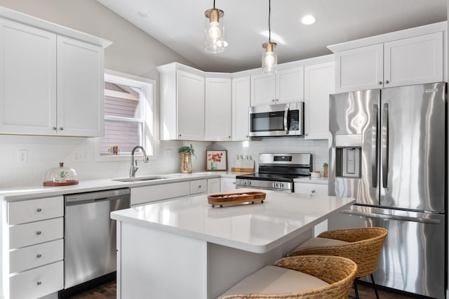 kitchen featuring lofted ceiling, sink, pendant lighting, appliances with stainless steel finishes, and a center island