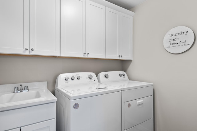 clothes washing area featuring cabinets, washing machine and dryer, and sink