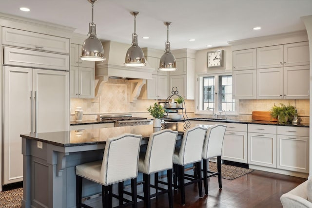 kitchen featuring hanging light fixtures, a center island with sink, stainless steel gas stovetop, and dark hardwood / wood-style floors