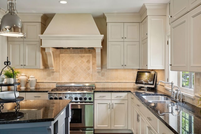 kitchen featuring custom exhaust hood, sink, high end stainless steel range, decorative light fixtures, and dark stone countertops