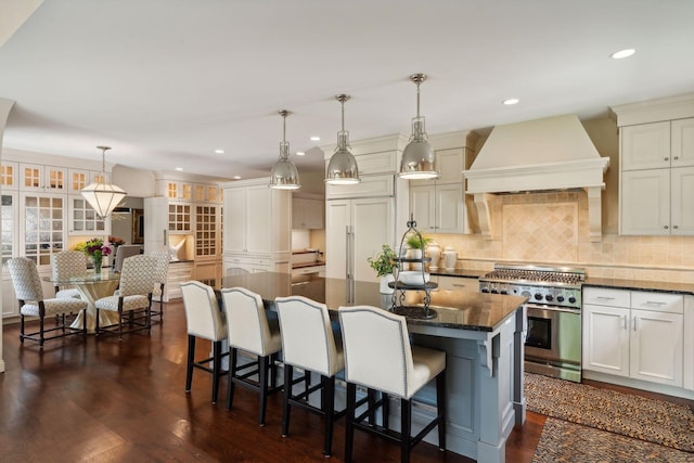 kitchen featuring custom range hood, a kitchen island, decorative light fixtures, high end range, and dark hardwood / wood-style floors