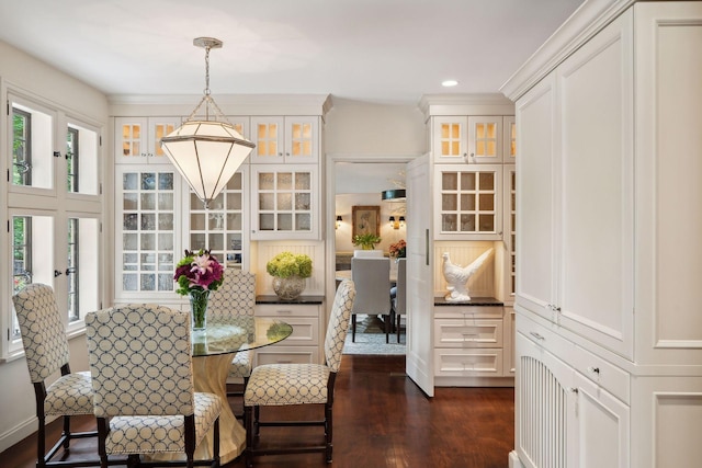 dining space with ornamental molding and dark wood-type flooring