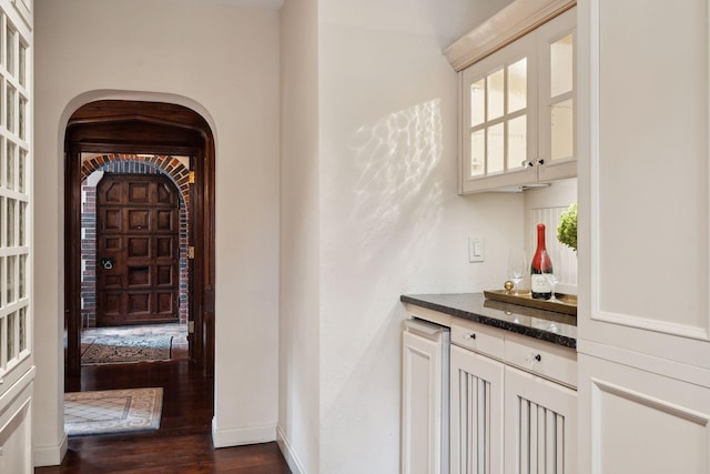 interior space with dark stone counters, dark hardwood / wood-style flooring, white cabinetry, and a wealth of natural light