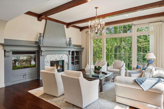 living room featuring beamed ceiling, light hardwood / wood-style flooring, a premium fireplace, and a notable chandelier