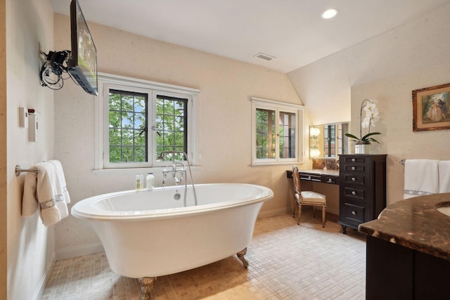 bathroom with a bathtub, vanity, and vaulted ceiling