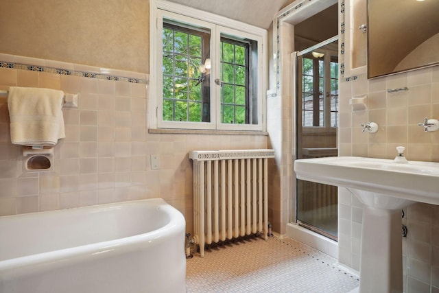 bathroom featuring tile walls, separate shower and tub, radiator heating unit, and tile patterned floors