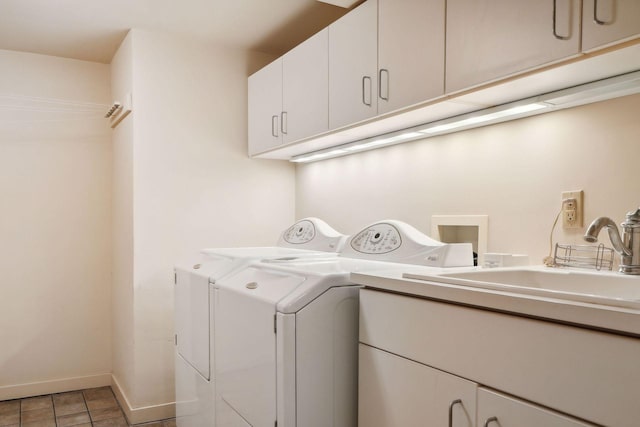 clothes washing area featuring tile patterned flooring, sink, washing machine and clothes dryer, and cabinets