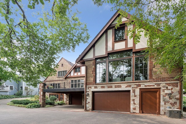 tudor house featuring central air condition unit and a garage