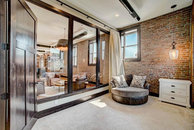 sitting room featuring light carpet and brick wall