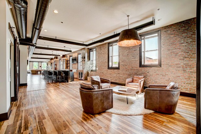 unfurnished living room featuring brick wall and light wood-type flooring