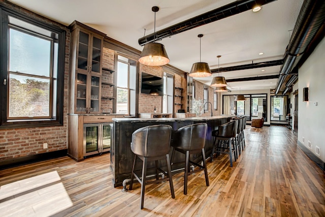 kitchen featuring a kitchen bar, decorative light fixtures, light hardwood / wood-style floors, and brick wall