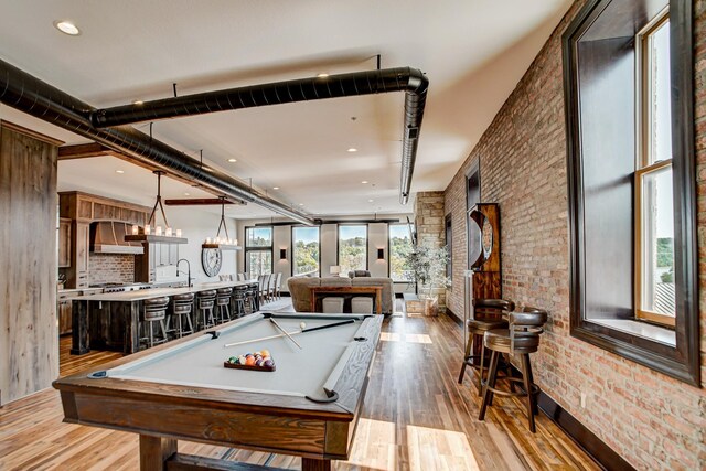 playroom featuring bar area, light wood-type flooring, pool table, and brick wall