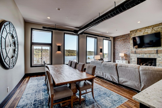 dining room with a stone fireplace and dark hardwood / wood-style flooring