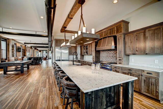 kitchen featuring high end appliances, a spacious island, light wood-type flooring, and custom exhaust hood