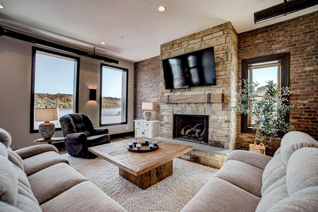 living room featuring a stone fireplace and brick wall