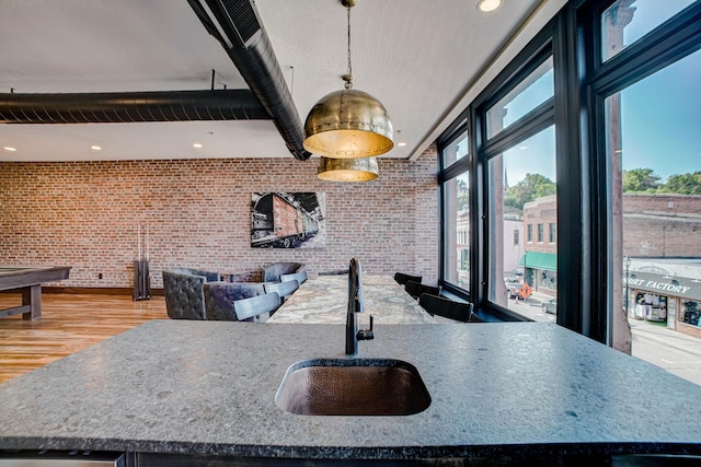 kitchen with sink, light hardwood / wood-style flooring, brick wall, pendant lighting, and pool table