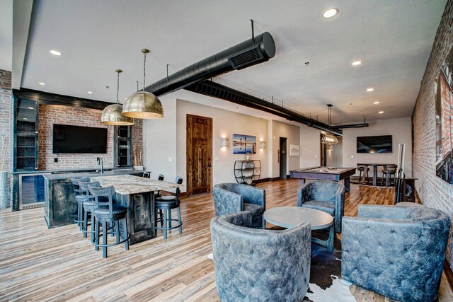 living room with sink, light hardwood / wood-style flooring, brick wall, and billiards