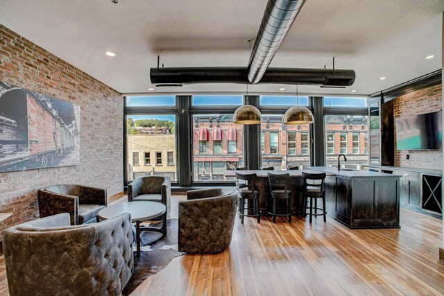 living room featuring brick wall, light hardwood / wood-style flooring, plenty of natural light, and sink