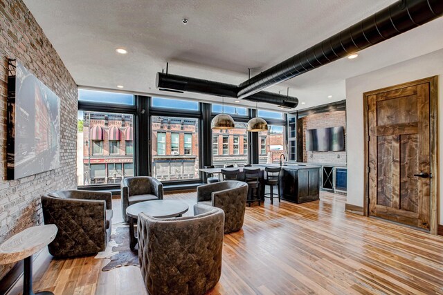 living room featuring a textured ceiling, light hardwood / wood-style flooring, and brick wall