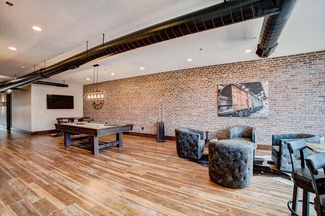 playroom featuring billiards, light wood-type flooring, and brick wall