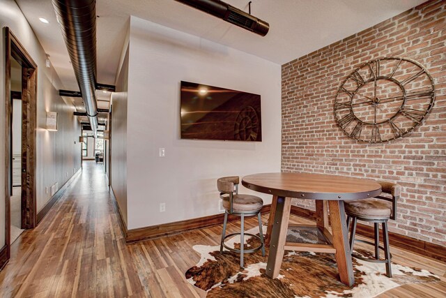 dining area featuring hardwood / wood-style floors and brick wall