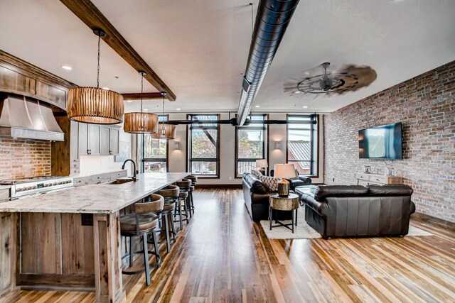 kitchen featuring plenty of natural light, extractor fan, brick wall, and light wood-type flooring