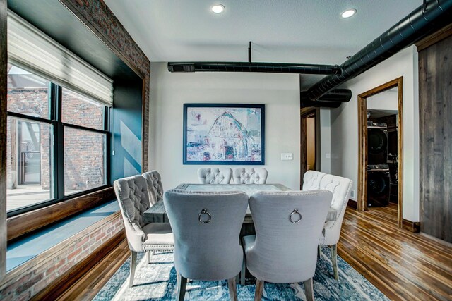 dining area featuring stacked washer / dryer, hardwood / wood-style floors, and a textured ceiling