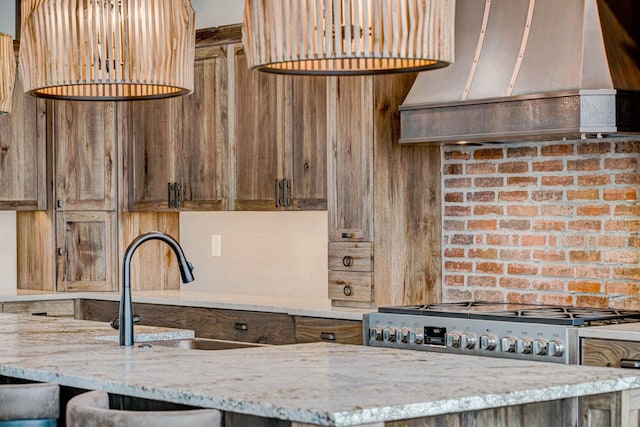 kitchen featuring brick wall, sink, light stone counters, and custom exhaust hood