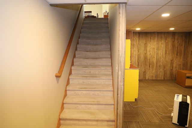 stairway featuring carpet flooring and a drop ceiling