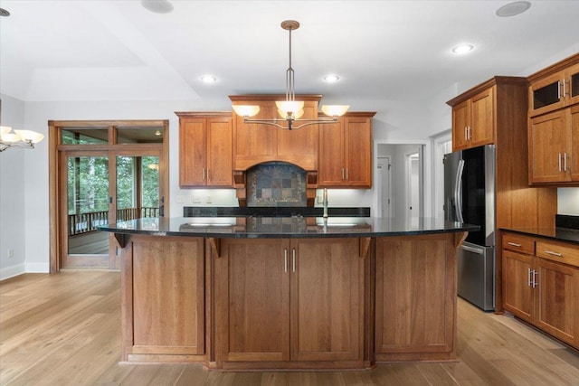 kitchen featuring light wood-type flooring, a center island, stainless steel fridge, and a notable chandelier