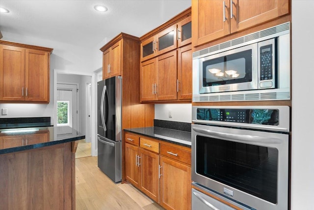 kitchen featuring light wood-type flooring, dark stone counters, and stainless steel appliances