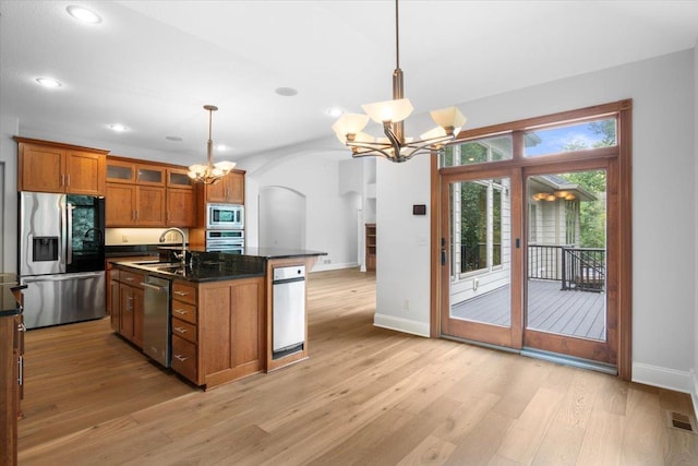 kitchen with decorative light fixtures, sink, appliances with stainless steel finishes, and a kitchen island with sink