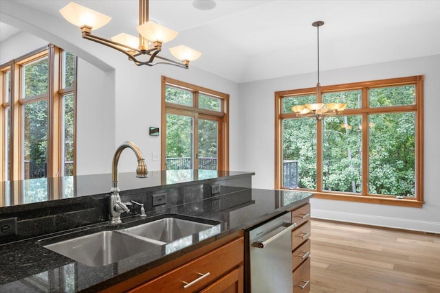 kitchen with hanging light fixtures, stainless steel dishwasher, dark stone counters, and a notable chandelier