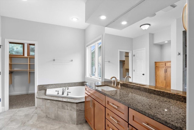 bathroom featuring tiled tub and vanity