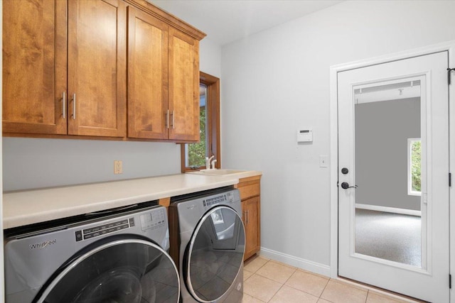 laundry room with cabinets, light tile patterned floors, sink, and washing machine and dryer