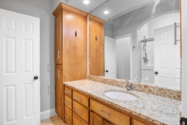 bathroom with tile patterned flooring, walk in shower, and vanity