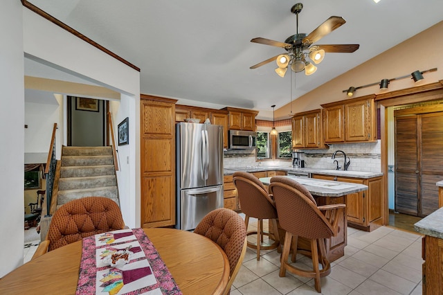 kitchen with hanging light fixtures, vaulted ceiling, a kitchen island, stainless steel appliances, and ceiling fan