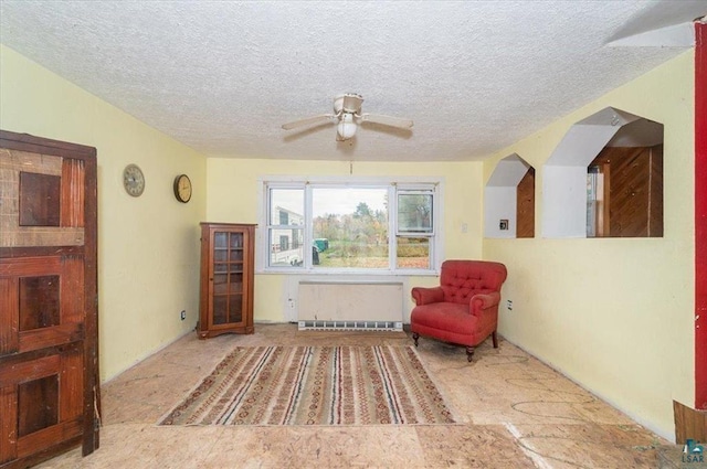 living area with ceiling fan and a textured ceiling