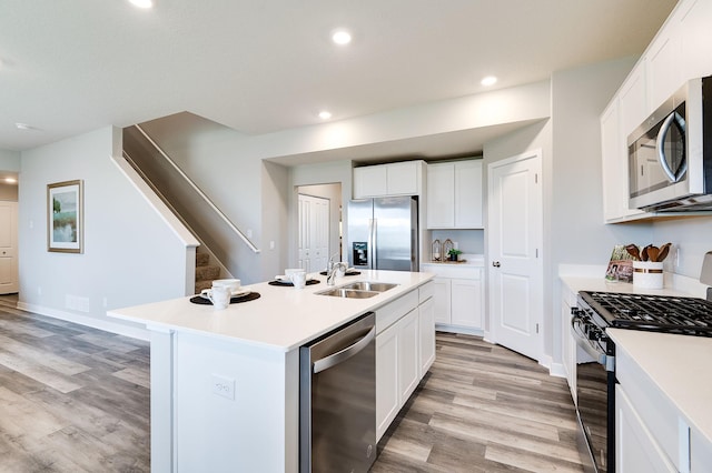 kitchen featuring appliances with stainless steel finishes, light hardwood / wood-style flooring, a center island with sink, and sink