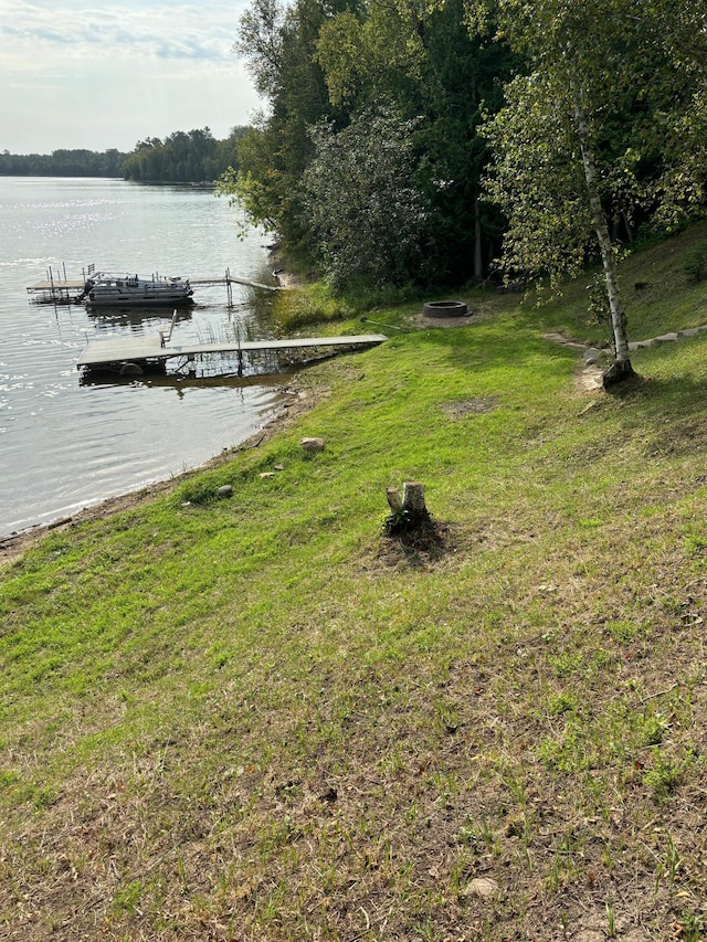 dock area with a lawn and a water view