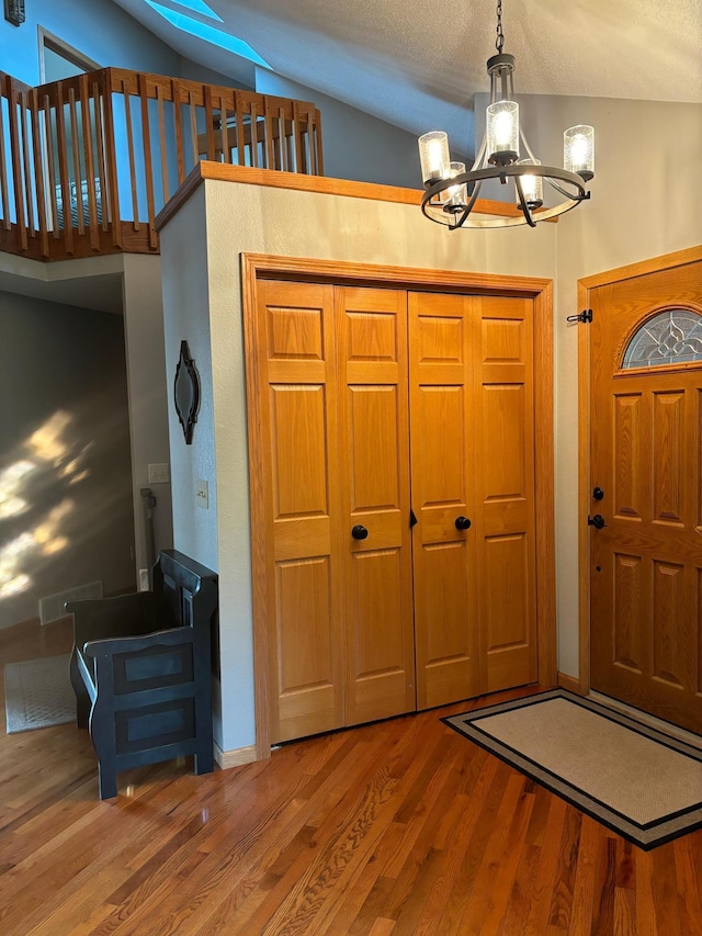 entryway featuring lofted ceiling, an inviting chandelier, hardwood / wood-style flooring, and a textured ceiling
