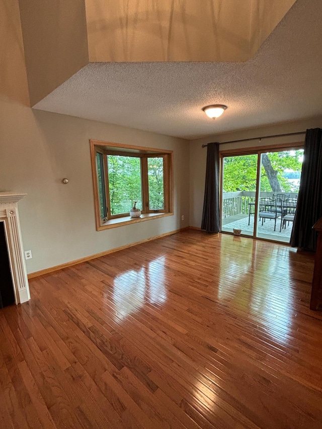 unfurnished living room featuring a textured ceiling, hardwood / wood-style floors, and a fireplace